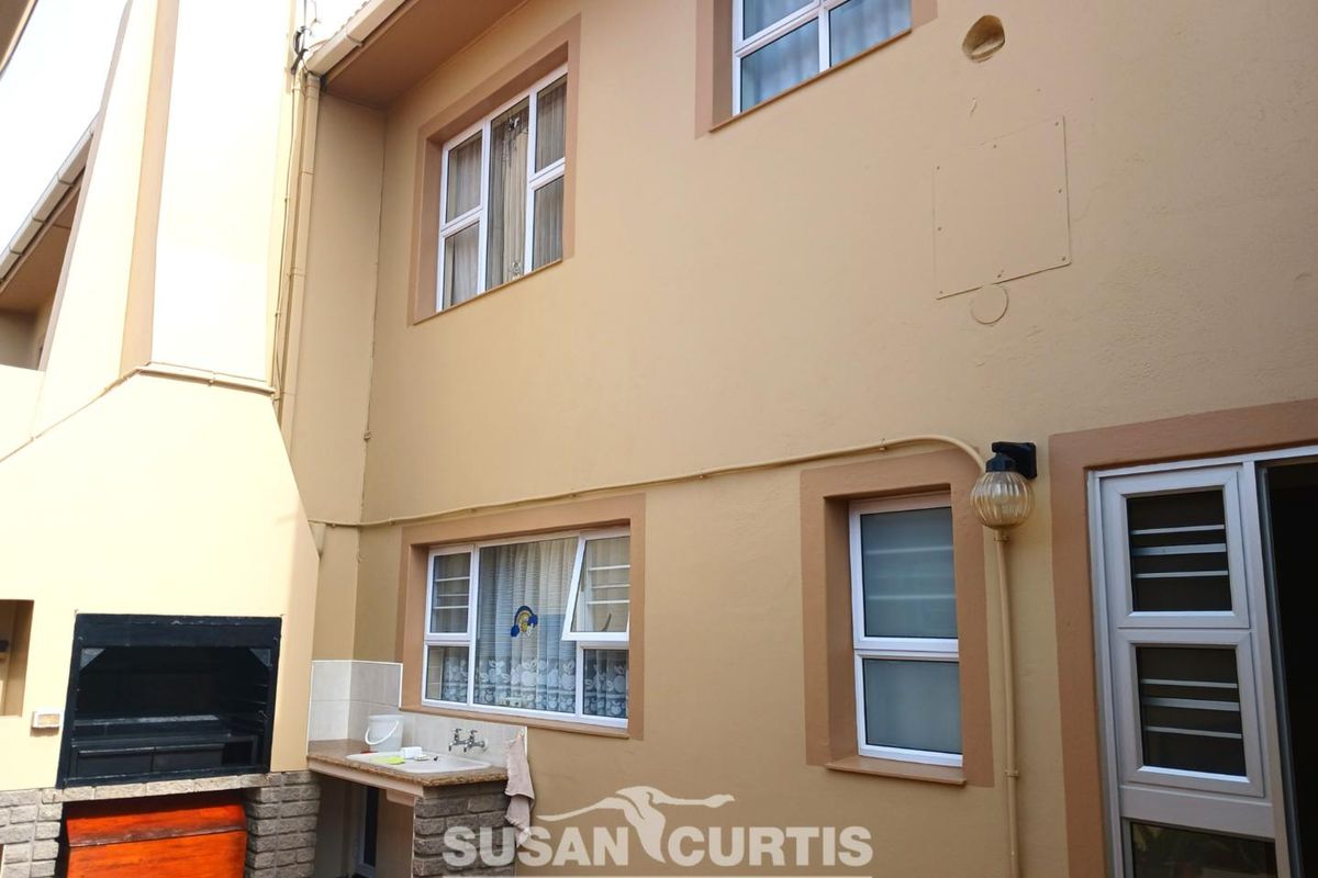 Rear exterior view of the townhouse featuring a built-in braai area with a sink and access to the interior living space.