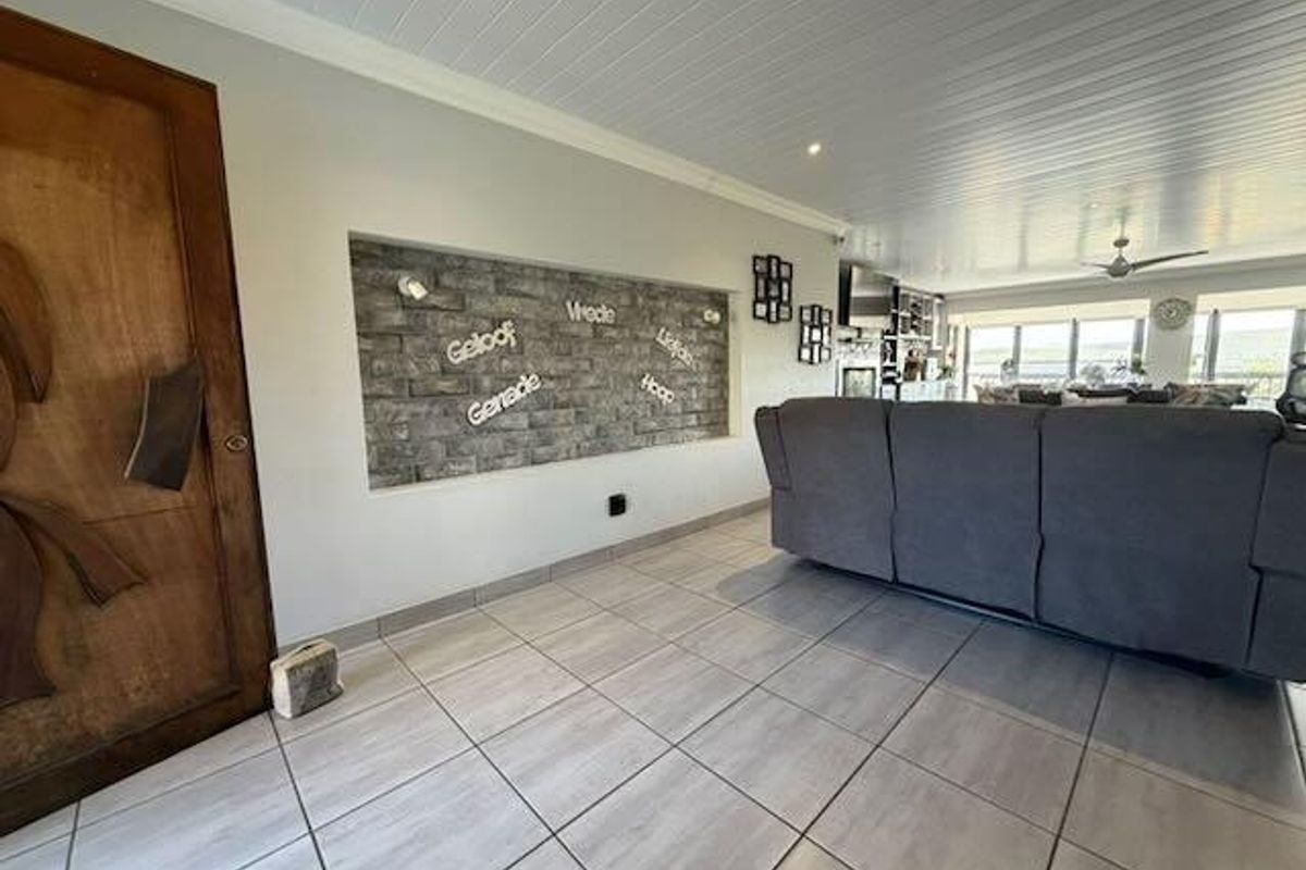 Spacious living area featuring a stone-clad feature wall, tiled flooring, and a tongue and groove ceiling with recessed lighting.