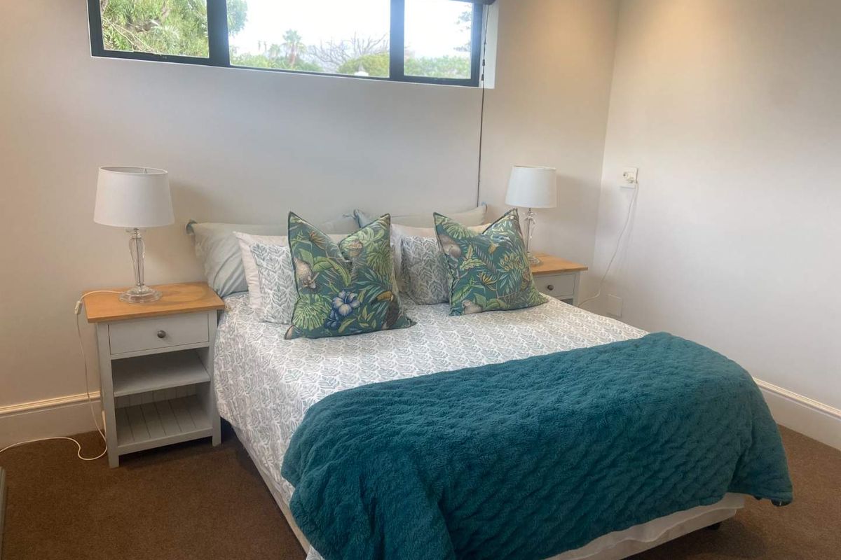 A well-maintained bedroom featuring neutral walls, carpeted flooring, and a high-set horizontal window providing natural light.