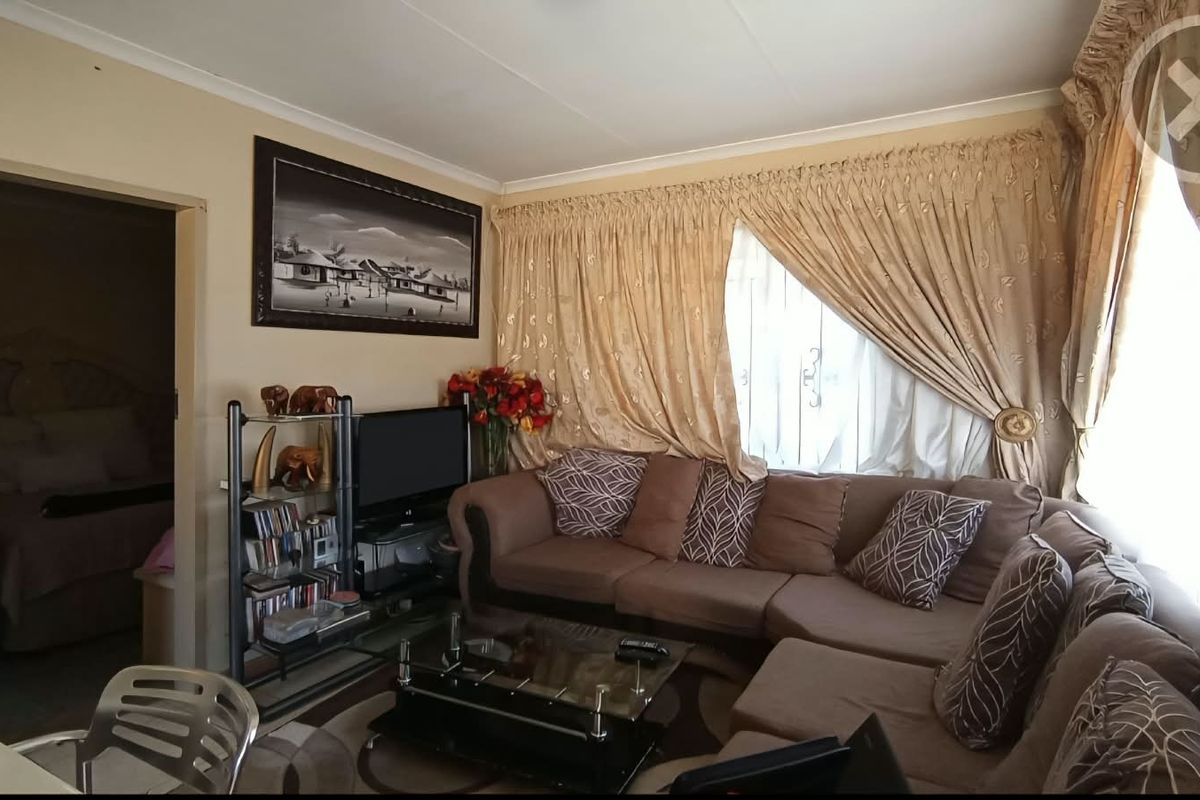 A comfortable living room featuring neutral wall tones, cove cornicing, and large window treatments, providing a functional and inviting space.