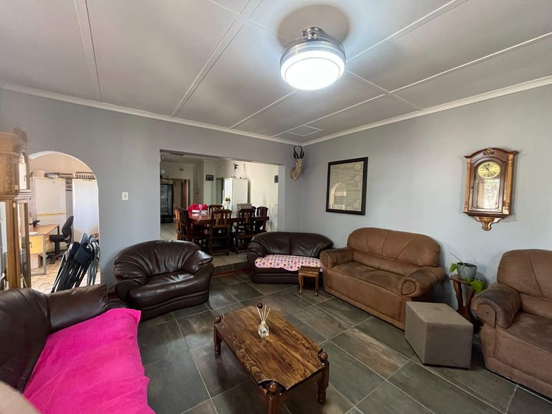 Open plan living area featuring tiled flooring, a panelled ceiling, and an arched entryway leading to an adjacent dining space.
