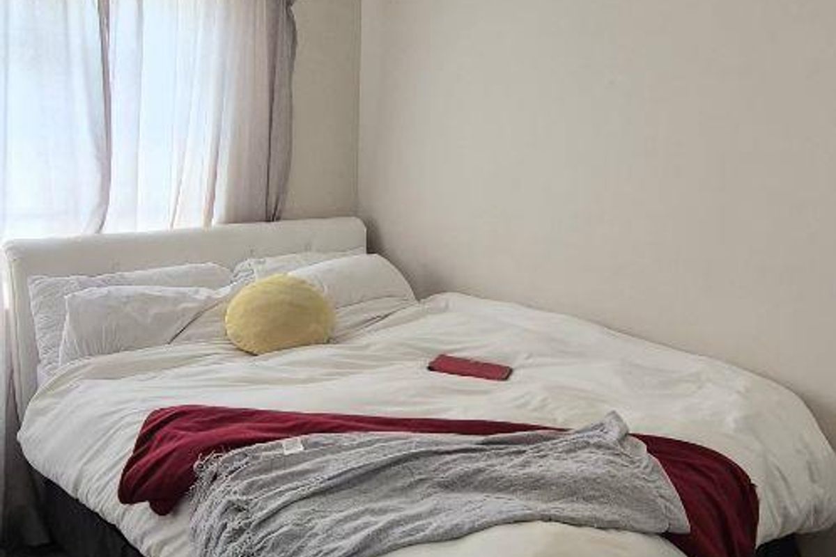 A compact bedroom featuring neutral wall tones and tiled flooring, providing a functional space for rest.