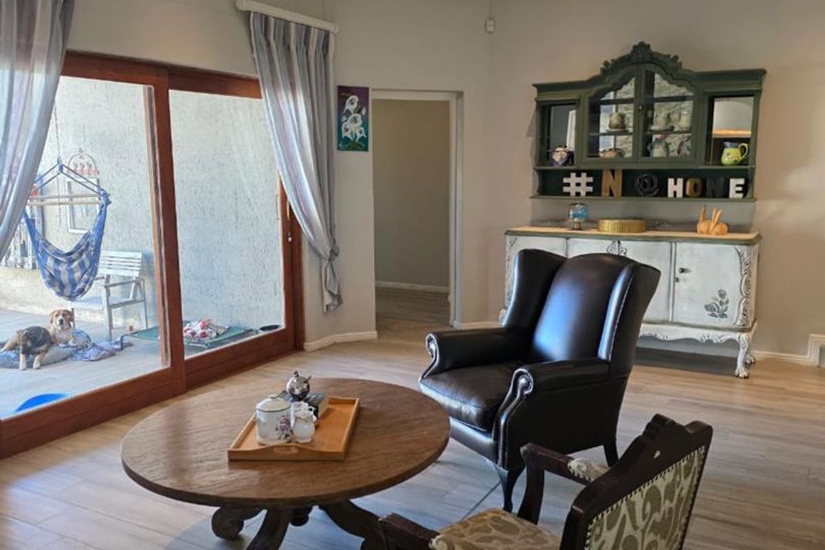 Spacious living room featuring wood-look tile flooring, recessed ceiling lighting, and large sliding glass doors providing direct access to the outdoor patio area.