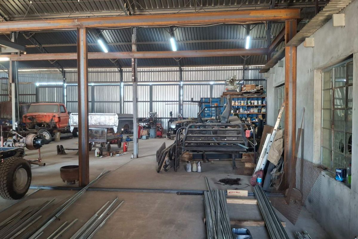 Spacious industrial workshop featuring a steel portal frame structure, corrugated metal walls, and concrete flooring, suitable for heavy-duty manufacturing or storage operations.