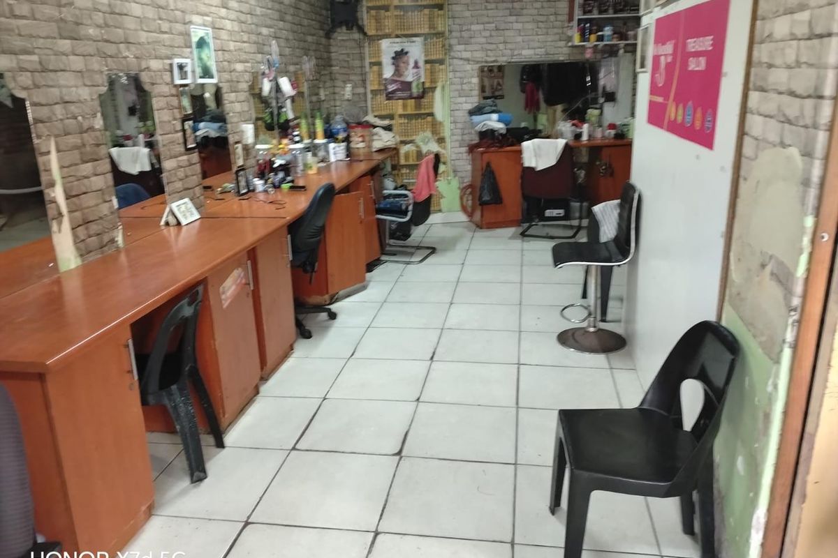 A commercial salon space featuring built-in vanity stations, wall-mounted mirrors, tiled flooring, and air conditioning, suitable for retail or beauty service operations.