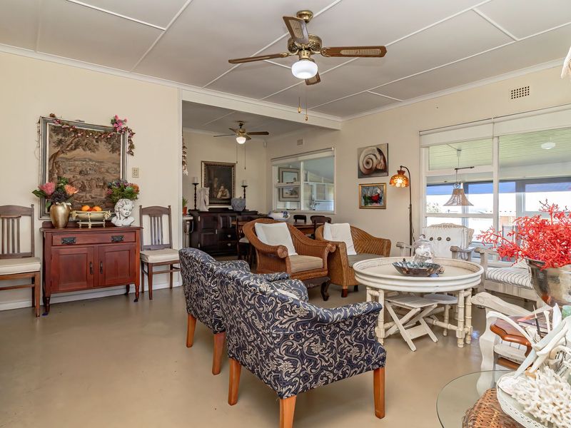A spacious living area featuring a ceiling fan, tiled ceiling, and large sliding glass doors that provide natural light and access to the outdoors.