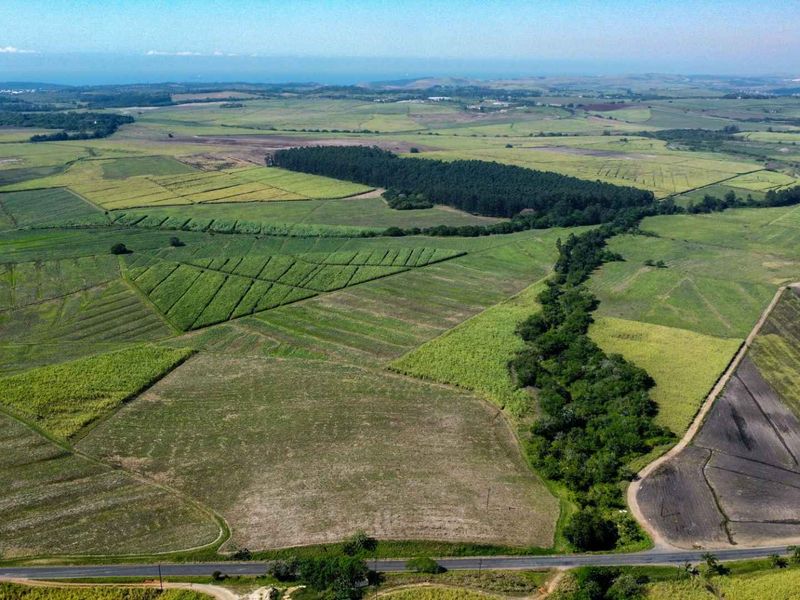 An expansive aerial view of the farm property featuring large agricultural fields, natural vegetation, and direct access to a public road.