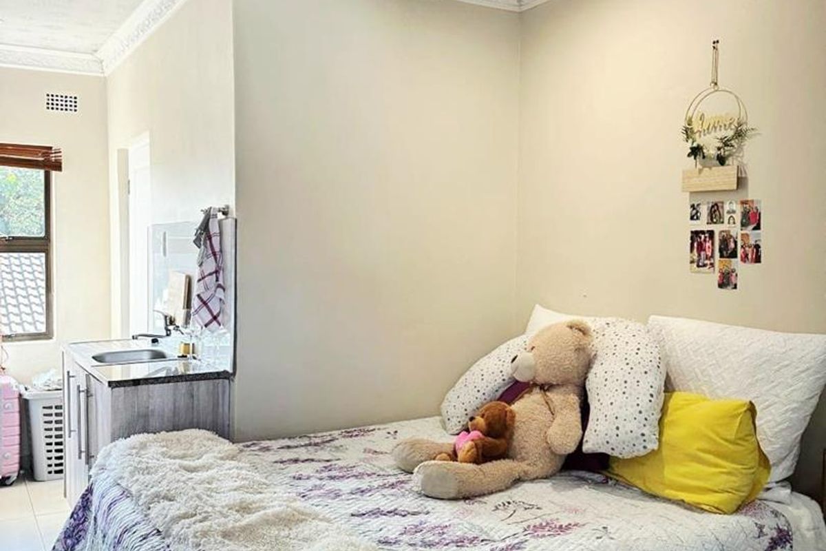 Bedroom featuring tiled flooring, decorative ceiling tiles, crown molding, and a compact built-in kitchenette area with a sink.