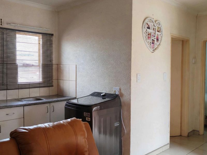 A functional kitchen area featuring built-in cabinetry, a stainless steel sink, tiled splashbacks, and an integrated oven, with adjacent access to other rooms.