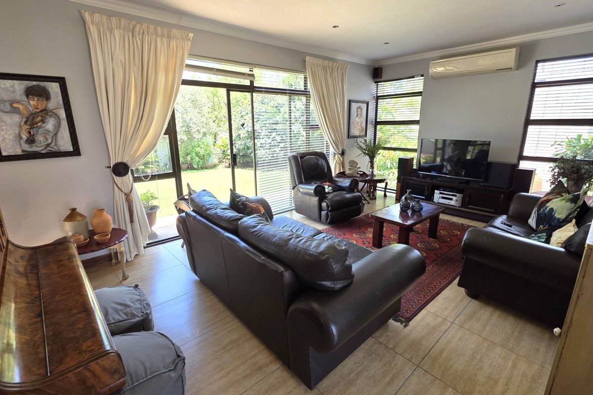 Spacious living room featuring large sliding glass doors that provide natural light and direct access to the garden, complemented by a wall-mounted air conditioning unit.