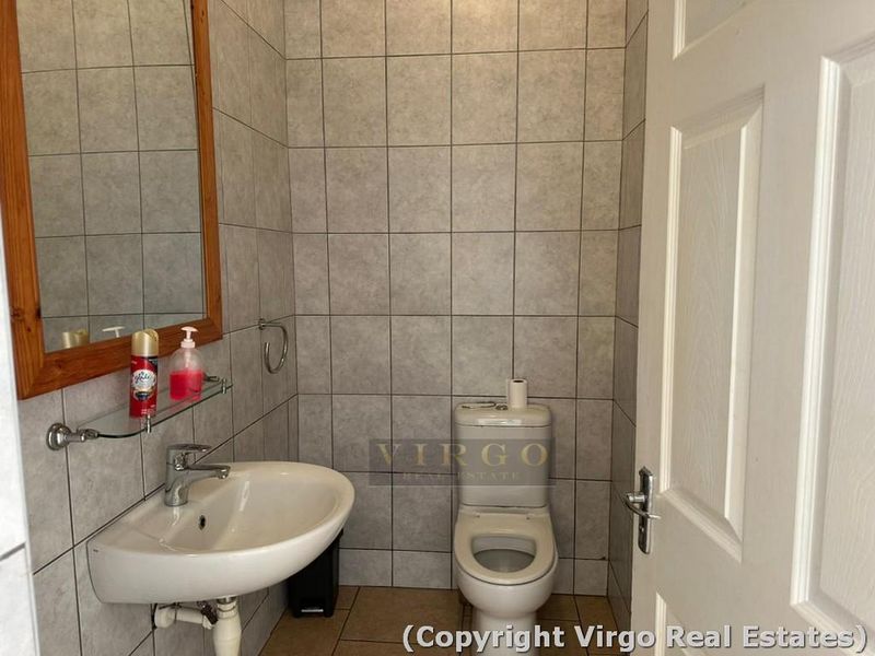 A functional bathroom featuring tiled walls and flooring, equipped with a wall-mounted basin and a standard toilet.