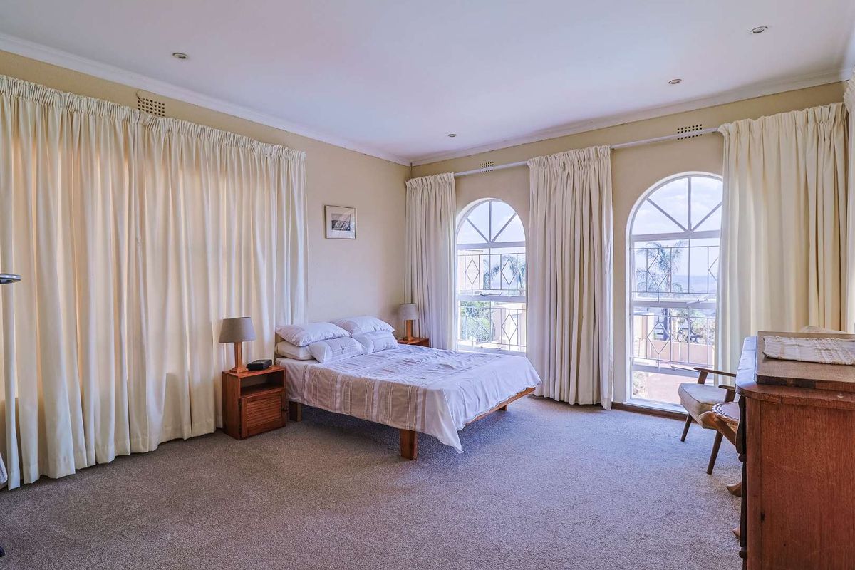Spacious bedroom featuring arched windows, neutral carpeting, and recessed ceiling lighting, offering a bright and comfortable living space.