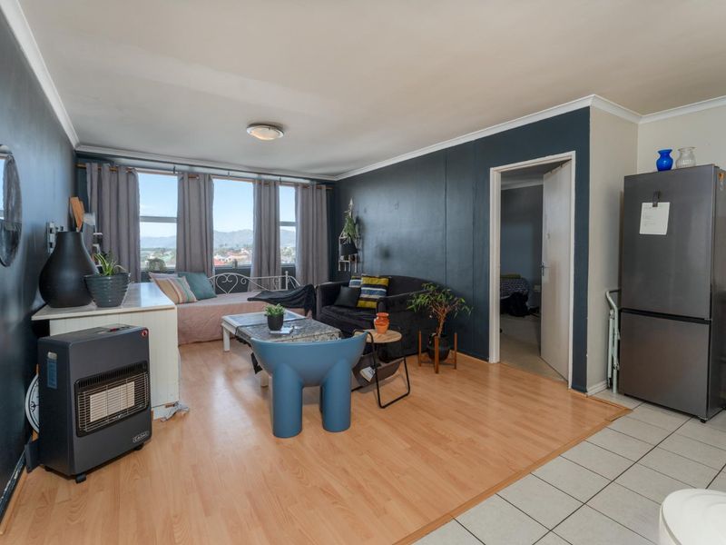 Open plan living area featuring a combination of laminate and tiled flooring with neutral wall finishes and access to adjacent rooms.