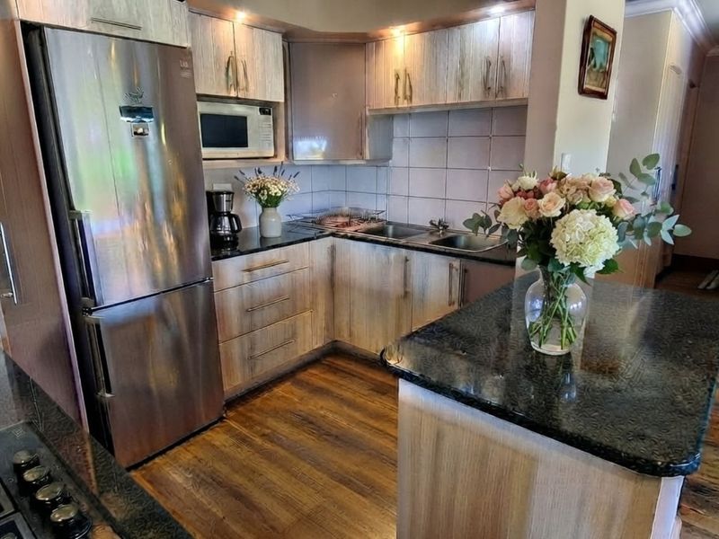 A well-appointed kitchen featuring wood-finish cabinetry, granite countertops, a central island, and integrated appliances, creating a functional and warm culinary space.