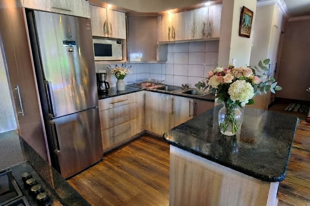 A well-appointed kitchen featuring wood-finish cabinetry, granite countertops, a central island, and integrated appliances, creating a functional and warm culinary space.