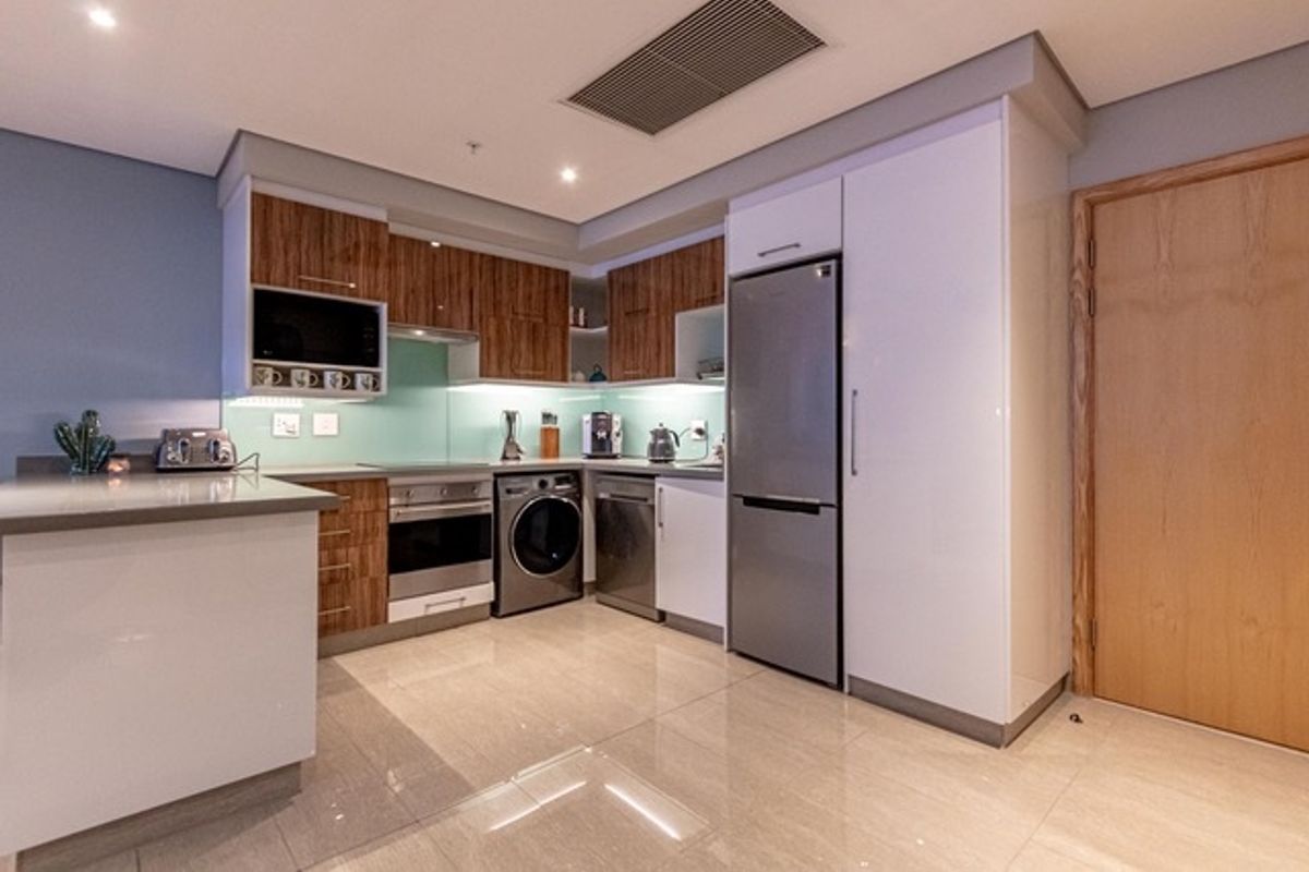 Modern kitchen featuring high-gloss cabinetry, integrated appliances, stone countertops, and recessed ceiling lighting in an open-plan layout.