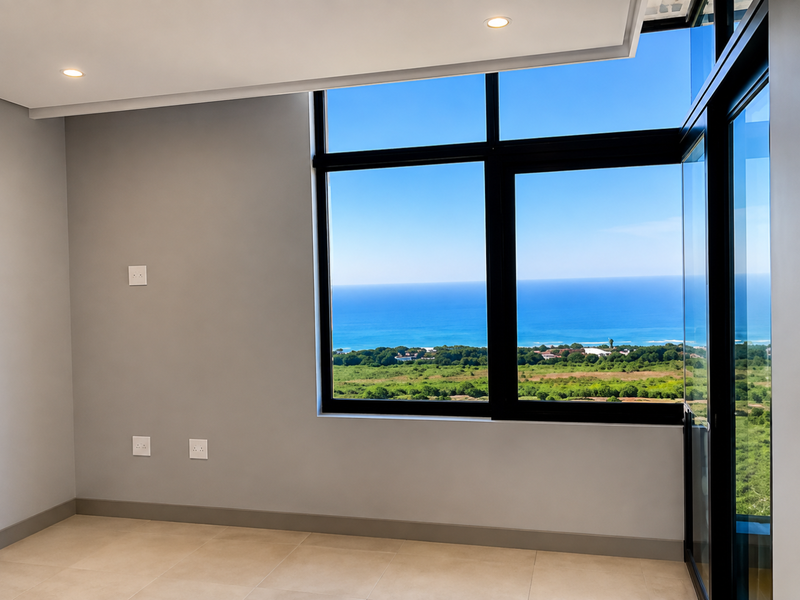 A bright, empty bedroom featuring large format floor tiles, recessed lighting, and expansive windows offering panoramic ocean and landscape views.