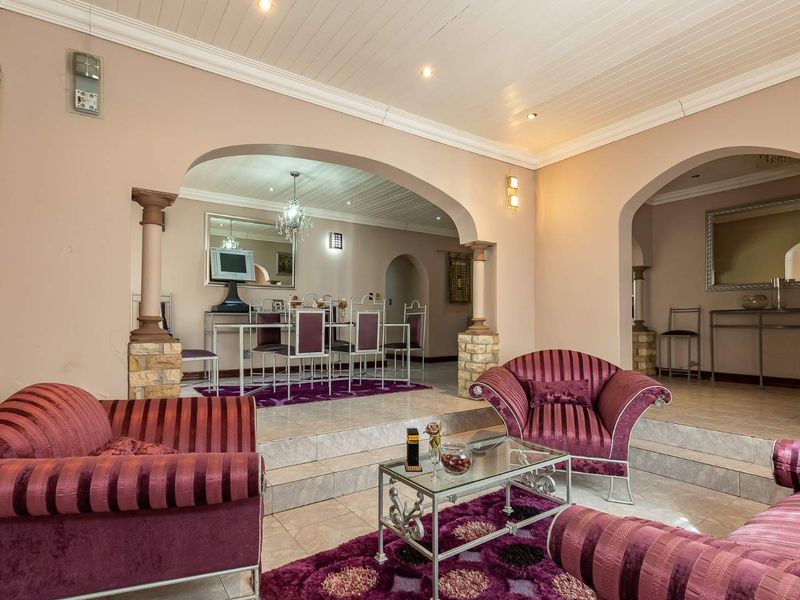 Spacious open-plan living and dining area featuring distinctive stone-clad columns, arched transitions, tiled flooring, and a classic tongue and groove ceiling.