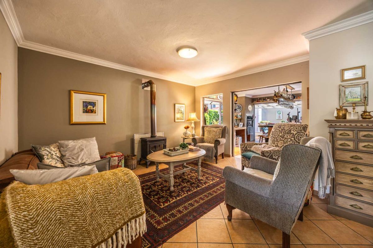 A cozy living room featuring ceramic tile flooring, crown molding, and a freestanding fireplace, with an open transition to the adjacent dining area.