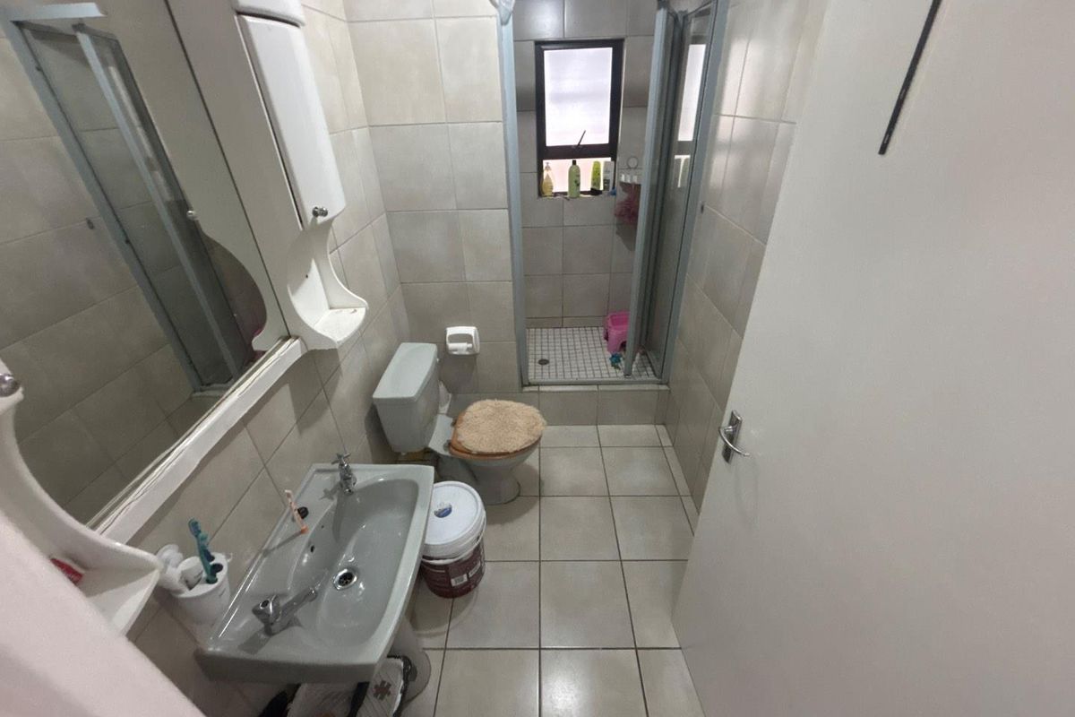 A compact bathroom featuring a pedestal basin, toilet, and a separate shower enclosure with tiled walls and flooring throughout.