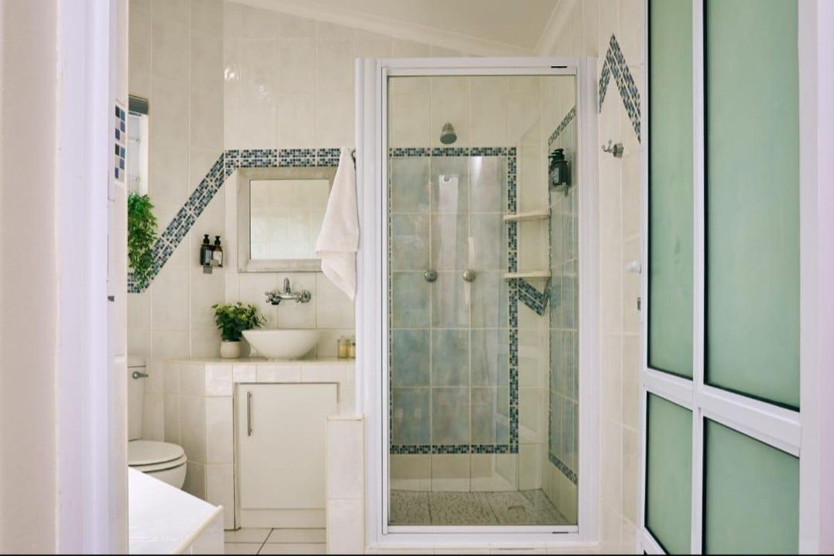 A functional bathroom featuring a glass-enclosed shower, built-in vanity with a vessel sink, and decorative tiled wall accents.