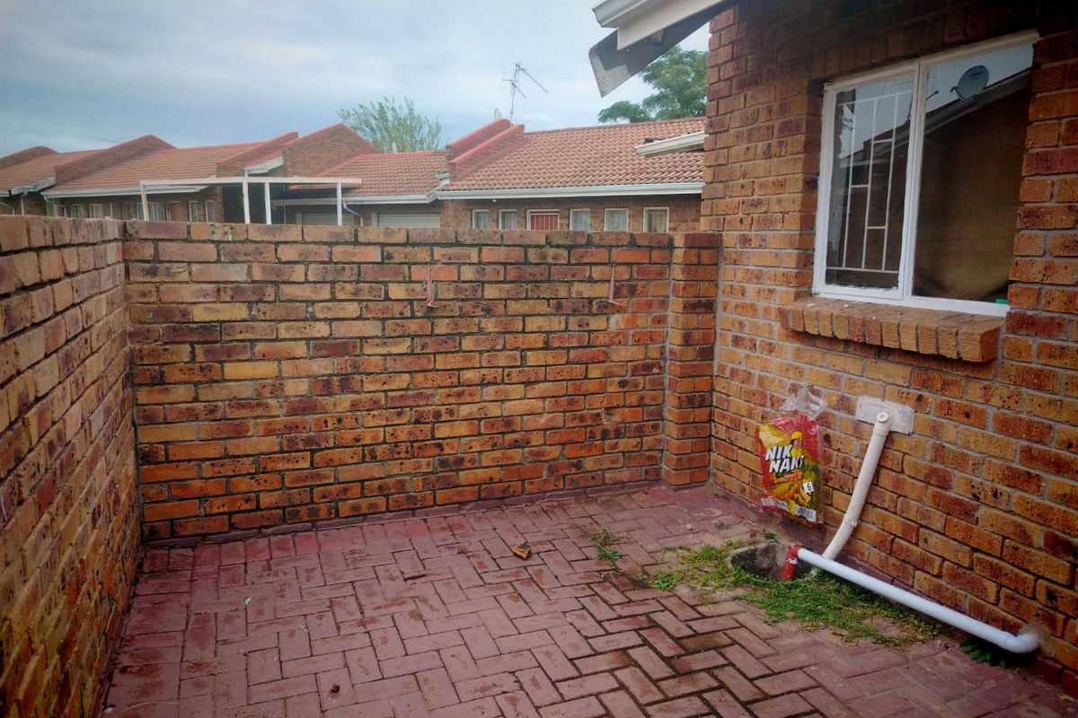 A small, private rear courtyard featuring brick walls and paved flooring, providing a compact outdoor space for the townhouse.