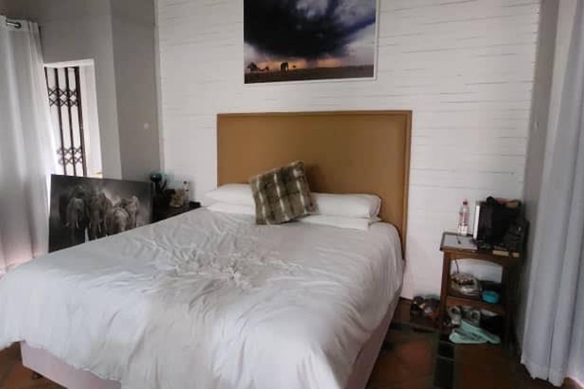 A bedroom featuring tiled flooring, a textured feature wall, and large windows with curtains.