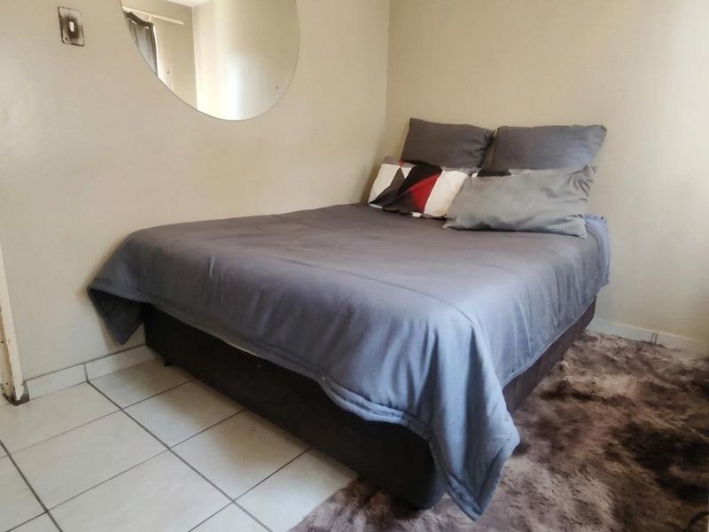 A compact bedroom featuring tiled flooring and neutral wall tones, providing a functional space for rest.