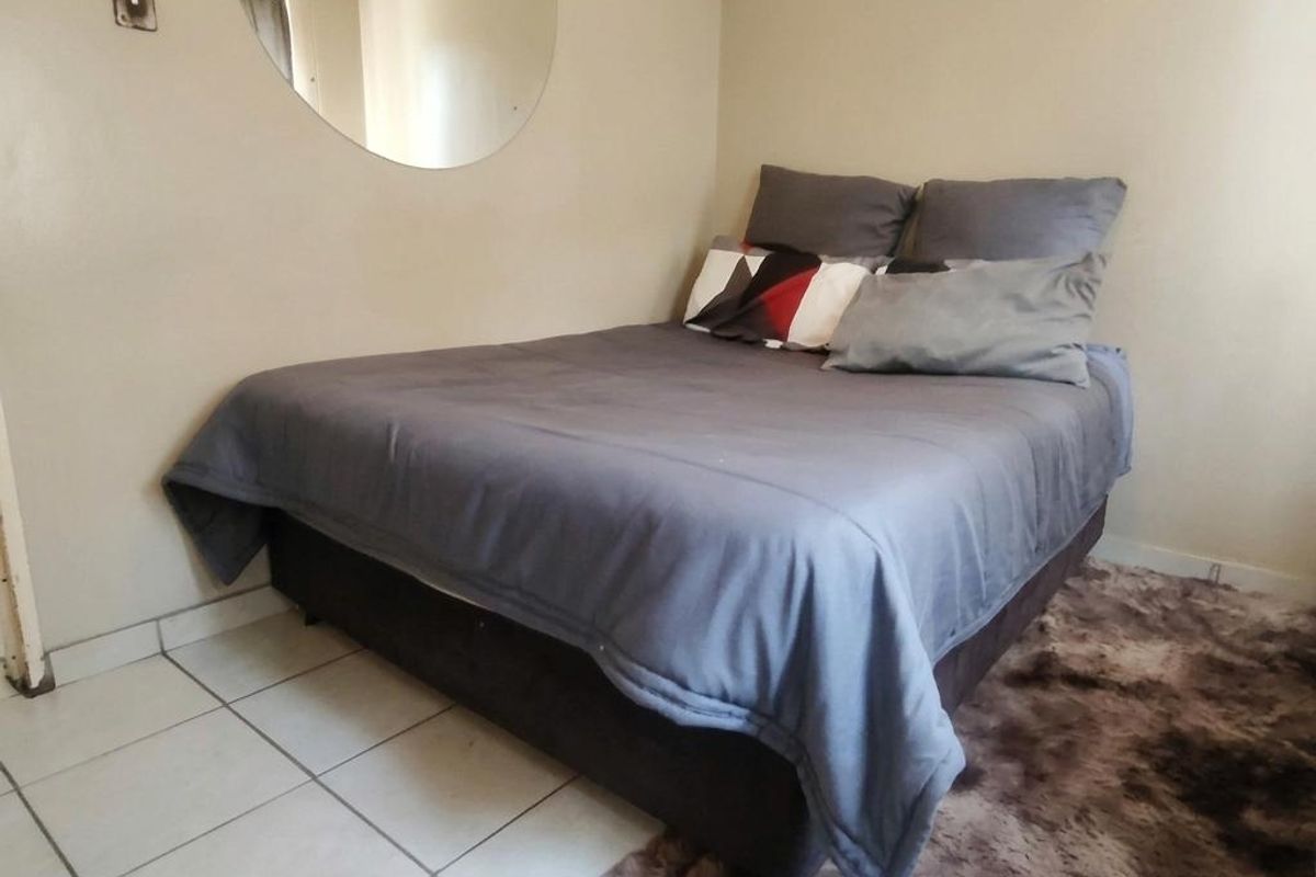 A compact bedroom featuring tiled flooring and neutral wall tones, providing a functional space for rest.