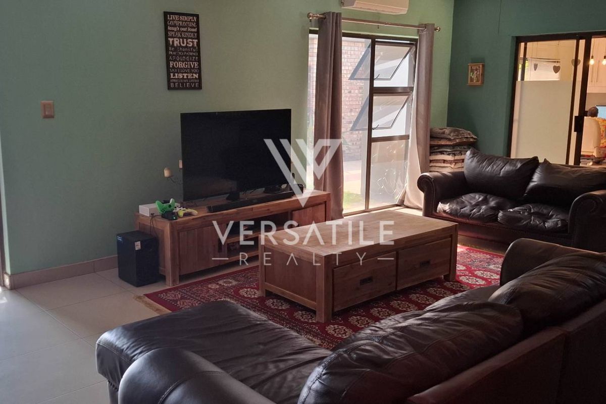 Spacious living room featuring tiled flooring, large sliding glass doors providing natural light, and direct access to an outdoor patio area.
