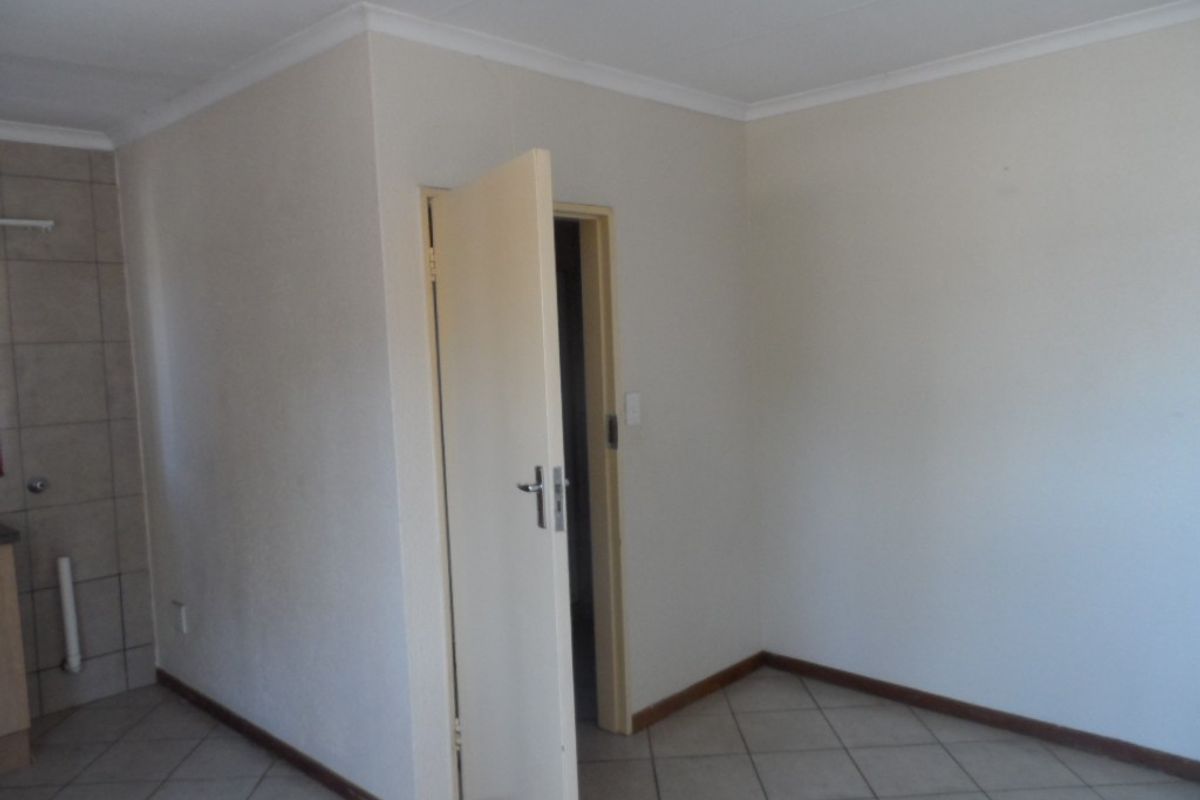 An empty living area featuring neutral walls, tiled flooring, and coved ceiling details, providing a blank canvas for interior design.