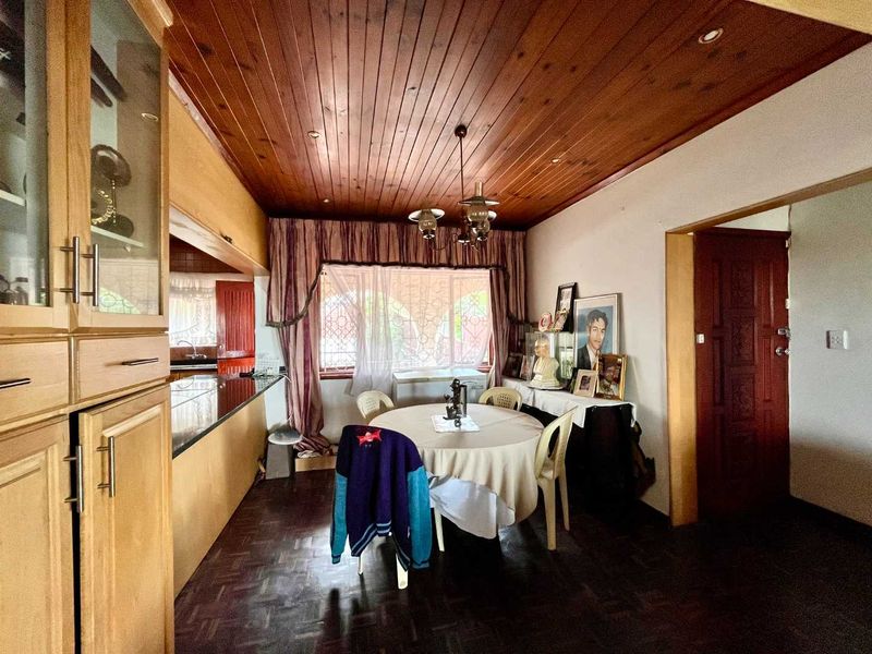 Open plan dining area featuring parquet flooring, timber ceiling, and built-in cabinetry with granite countertops, connecting to the kitchen space.