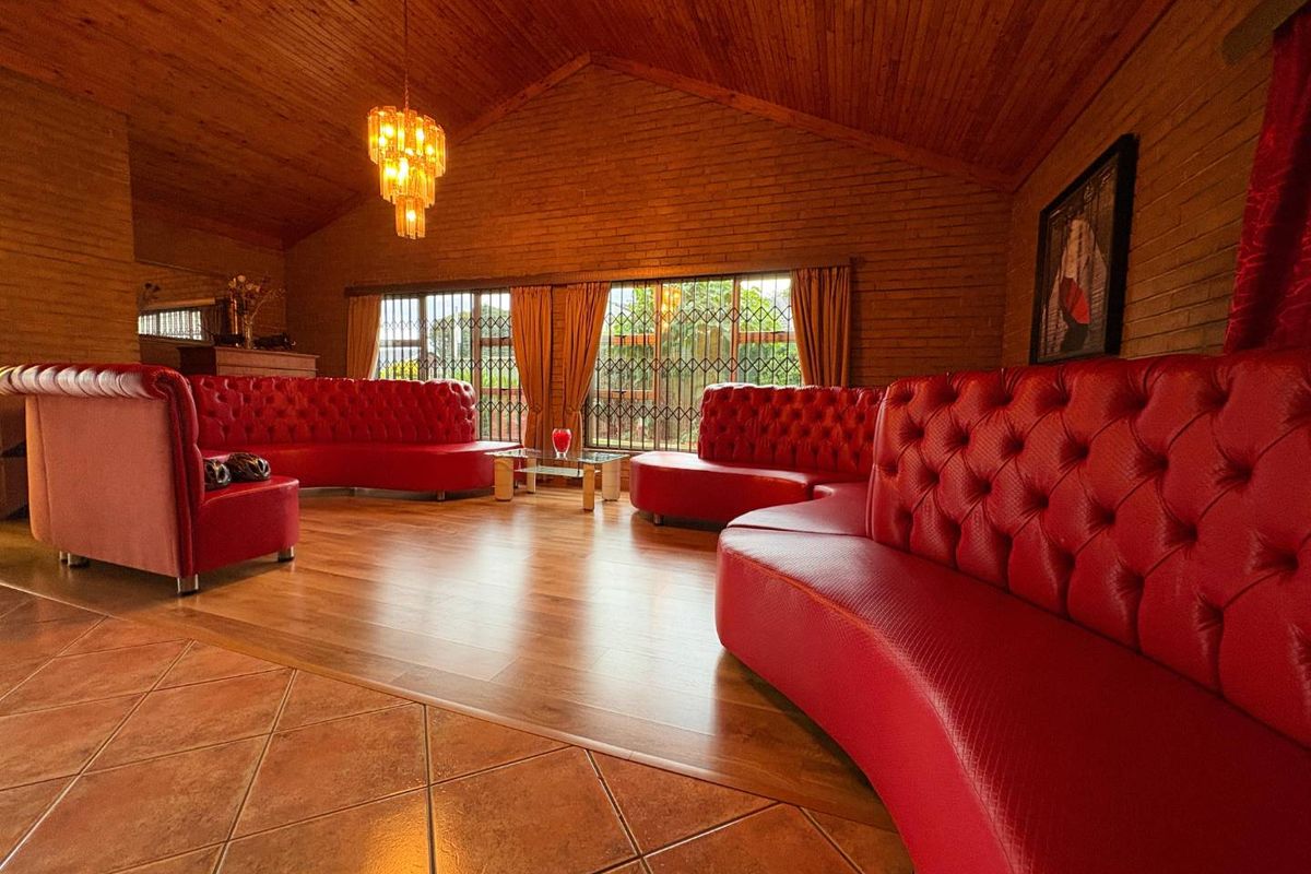 Spacious living room featuring exposed brick walls, a high timber vaulted ceiling, and a combination of laminate and tiled flooring.