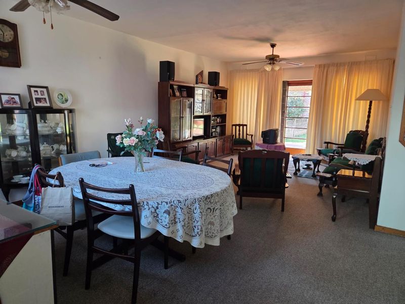 Spacious open-plan living and dining area featuring carpeted flooring, ceiling fans, and direct access to the outdoor space through a sliding glass door.