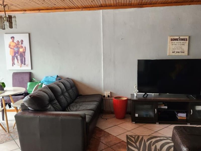 A living room featuring a timber tongue and groove ceiling and ceramic tiled flooring, offering a functional space for relaxation.