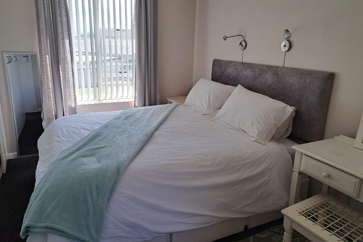 A well-lit bedroom featuring vertical blinds, wall-mounted reading lights, and neutral finishes, providing a comfortable and functional sleeping space.