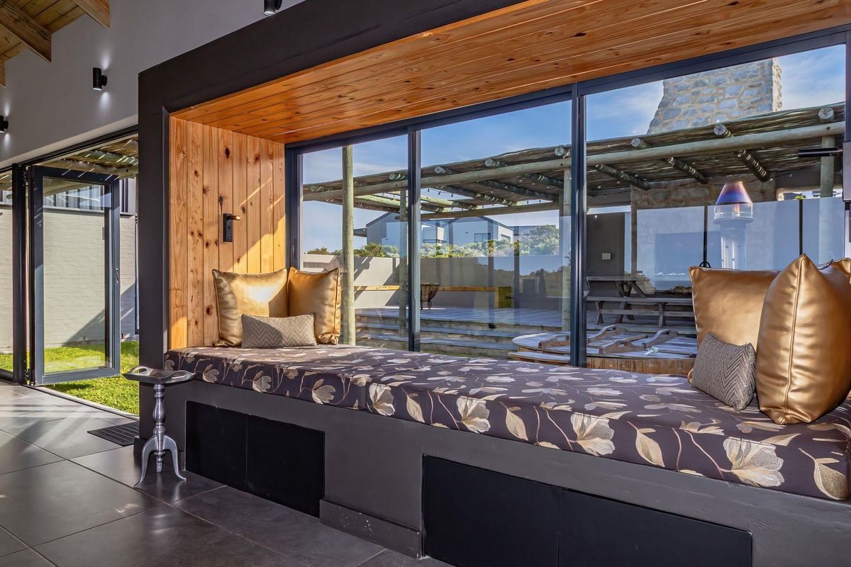 Modern living area featuring a custom built-in window seat with timber accents, large sliding doors, and high-quality tiled flooring overlooking the outdoor patio.