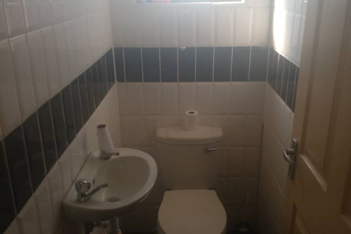 A compact guest bathroom featuring a wall-mounted basin, toilet, and classic black and white tiled walls.