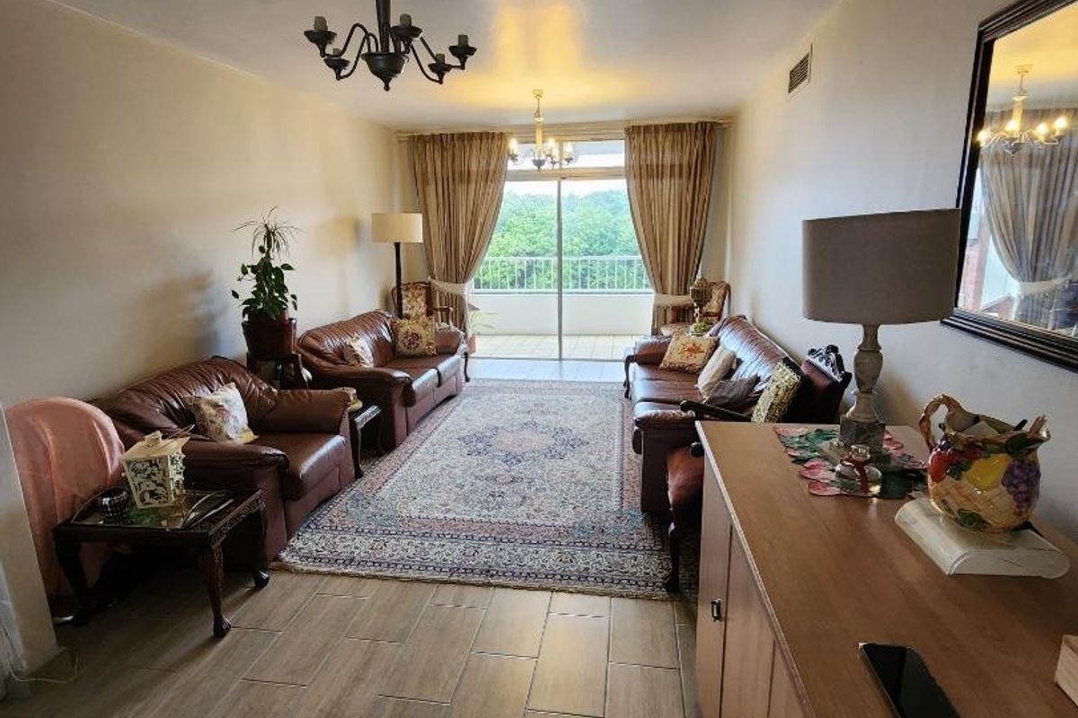 A spacious living room featuring tiled flooring and a sliding glass door that provides access to an outdoor balcony area.