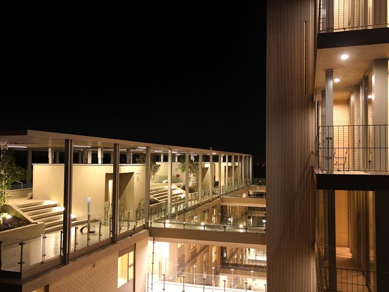 Night view of a modern apartment complex featuring multi-level terraces, glass balustrades, and architectural lighting.