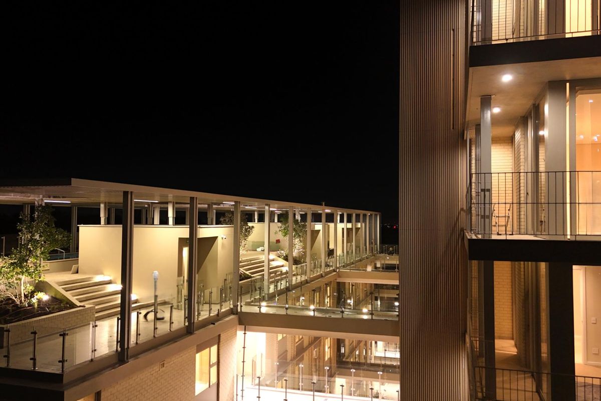 Night view of a modern apartment complex featuring multi-level terraces, glass balustrades, and architectural lighting.