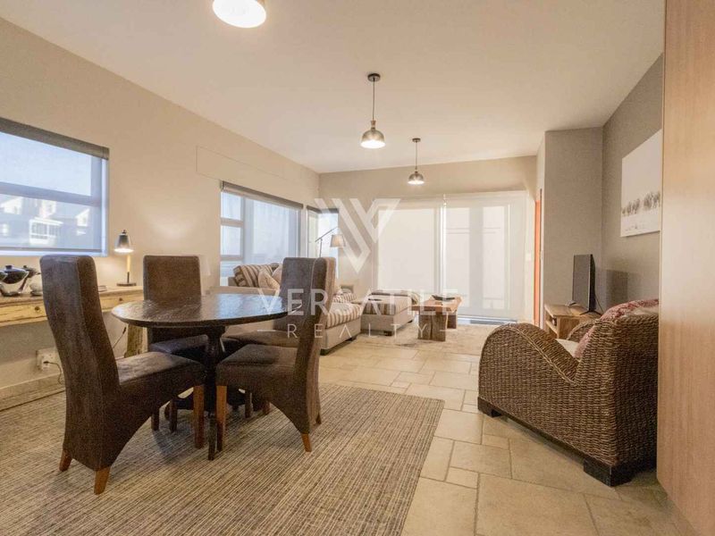 An open-plan living and dining area featuring tiled flooring, neutral walls, and sliding glass doors leading to an outdoor space.