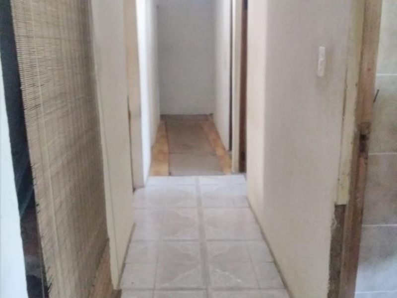 A narrow interior hallway featuring tiled flooring and exposed timber ceiling beams, currently in need of finishing and cosmetic updates.