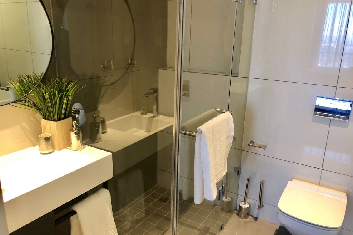 Modern bathroom featuring a floating vanity with integrated basin, glass-enclosed shower, and wall-mounted toilet with a sleek chrome flush plate.