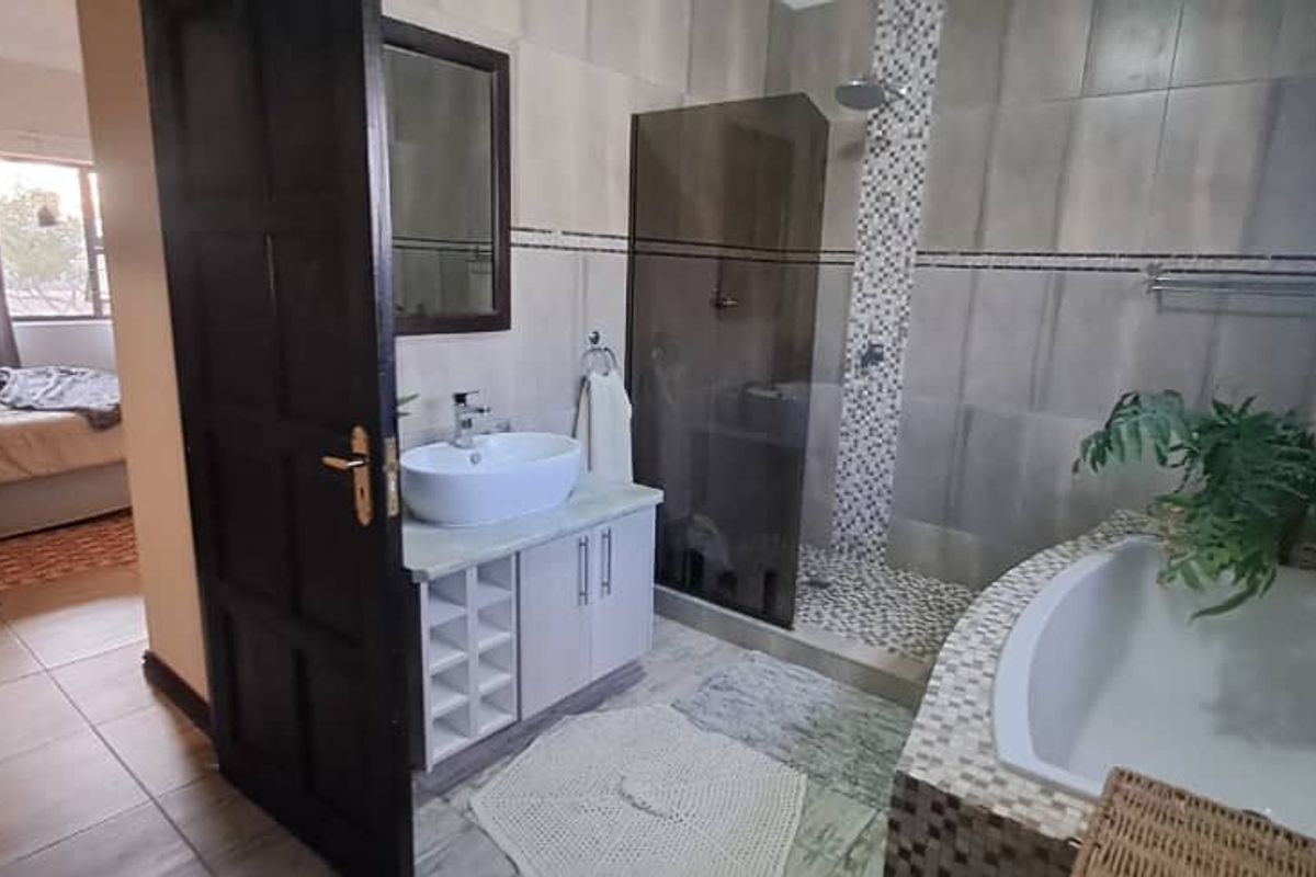 Modern bathroom featuring a vessel sink vanity, walk-in shower with mosaic detailing, and a built-in bathtub with tiled surround.