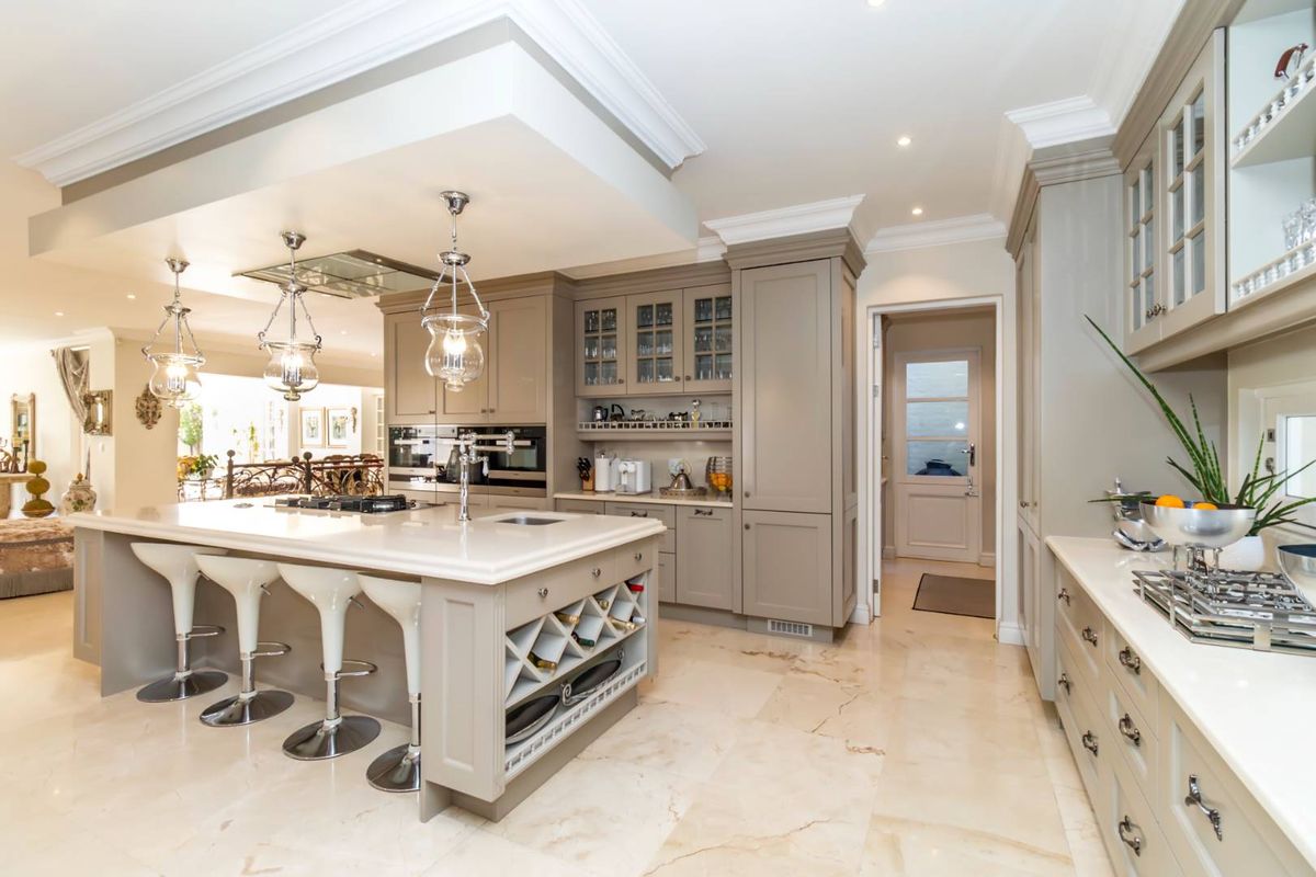 Spacious, high-end kitchen featuring a large central island with stone countertops, integrated appliances, custom cabinetry, and elegant pendant lighting.
