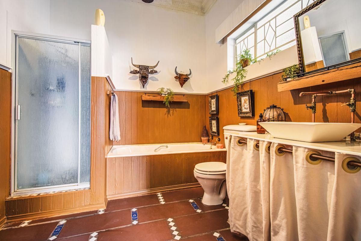 A bathroom featuring a built-in bathtub, separate shower enclosure, toilet, and a vessel sink vanity with copper plumbing fixtures.