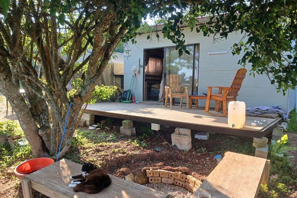 A raised timber deck patio area featuring a sliding glass door entrance, set within a natural garden environment.