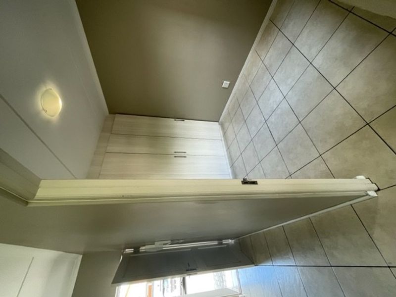 An empty bedroom featuring tiled flooring and built-in cupboards, providing a clean and functional space ready for personalization.