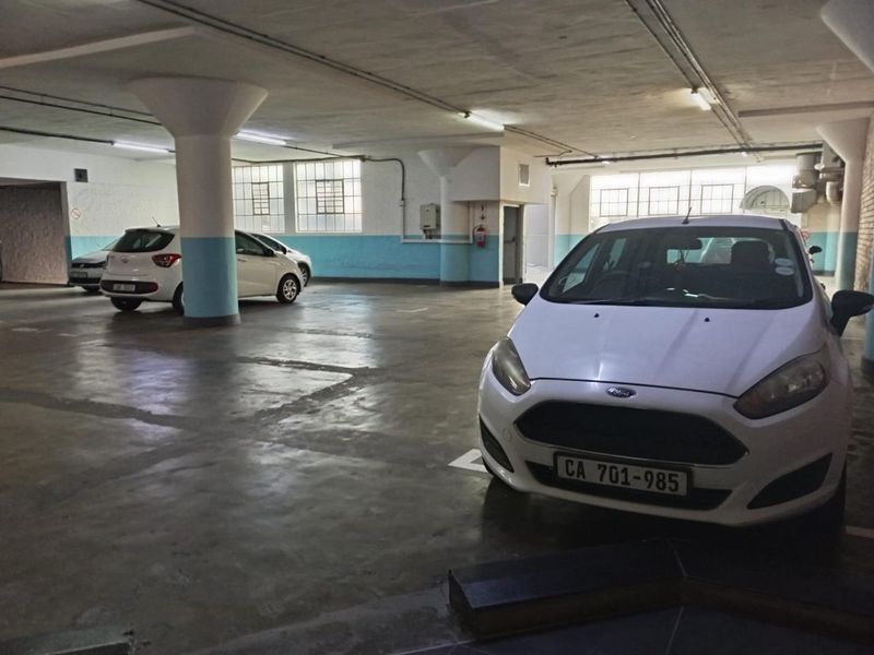 Underground parking garage area featuring concrete flooring, structural columns, and overhead fluorescent lighting.